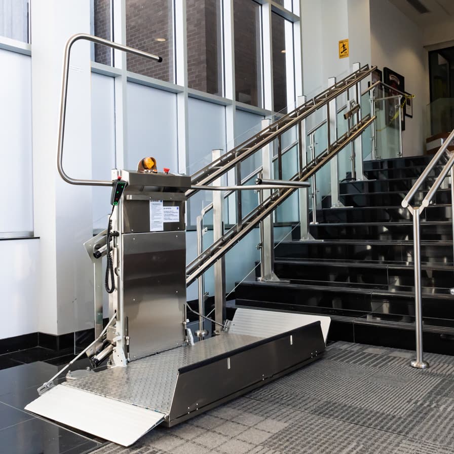 Delta straight stainless steel inclined platform lift providing accessibility on a contemporary glass and steel stairway.