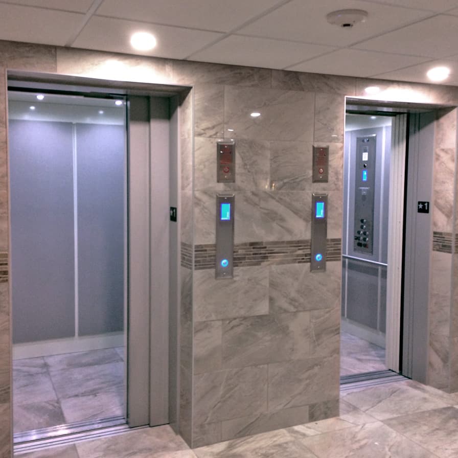Twin Orion LU/LA elevator entrances with automatic stainless steel doors, flush-mounted into a marble lobby wall.